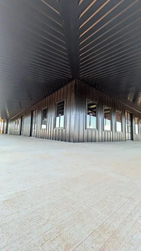Long dark steel barn with a covered porch and roll-up doors