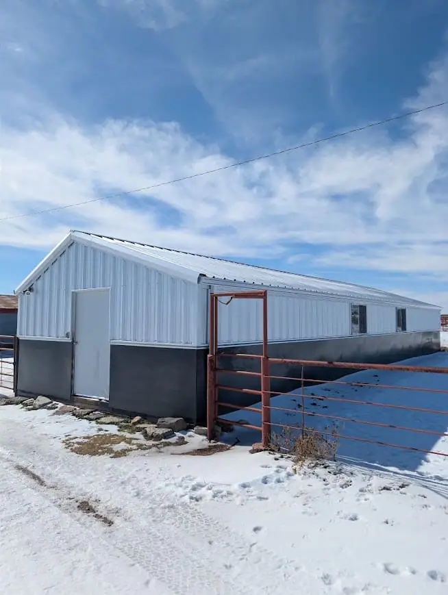 White steel shop with red trim, seen from the drive on a winter day