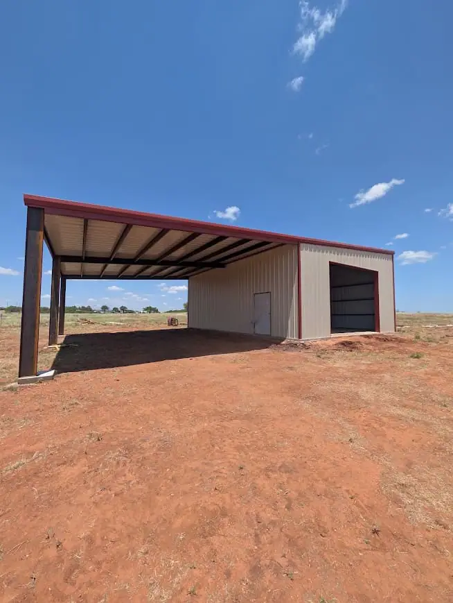 Tan steel shop with a red roof and a covered lean-to