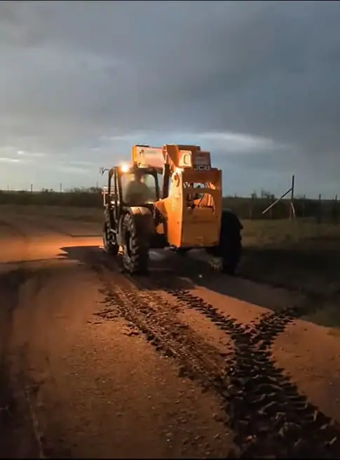 A Show Iron crew working a skid steer on a ranch build site at sunset