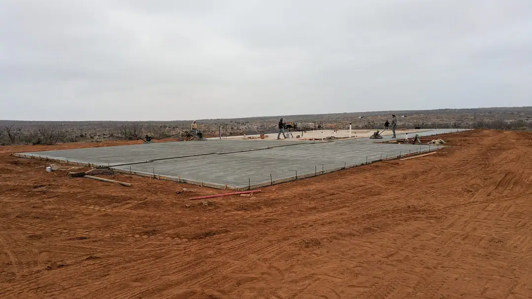 Long concrete slab on a ridge with the crew running power trowels