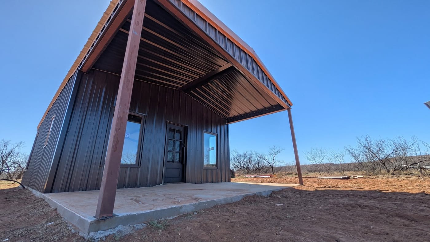 Corner of a dark brown steel building with a wide covered patio