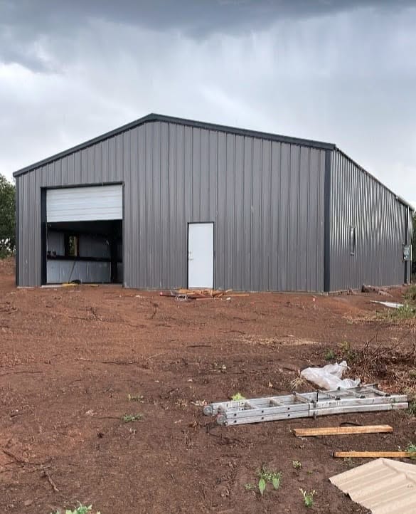 Grey steel shop with a white roll-up door under a stormy sky